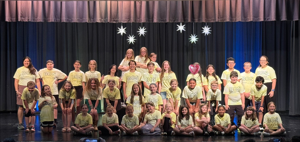 There is a group of students standing on a stage in the theater for a group picture during their drama camp.