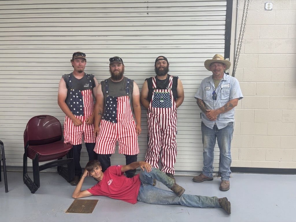 There are five people in the picture with three of them dressed in red, white and blue overalls and the other two dressed in red and blue.