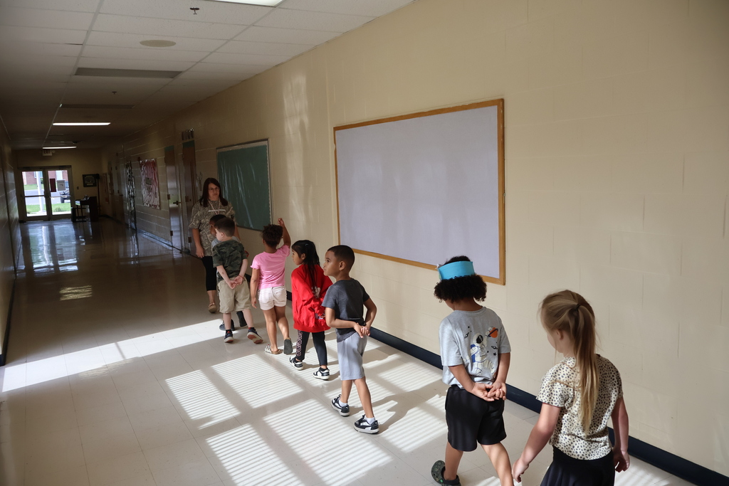 A teacher and her students are lined up in the hallway as they learn how they should be walking in it during school. 