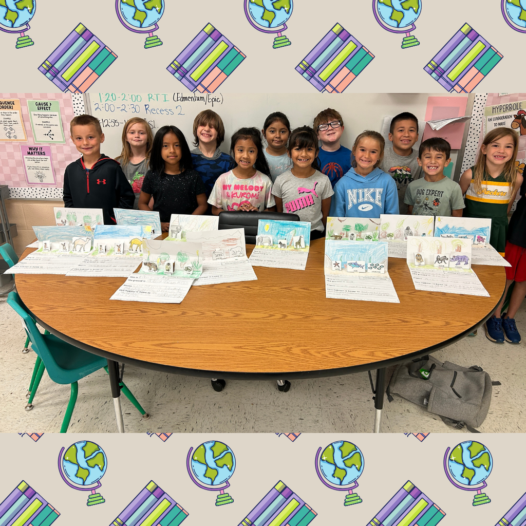 This is  a group picture of twelve students standing behind a table which is holding their dioramas from a habitats unit they have been learning about. 