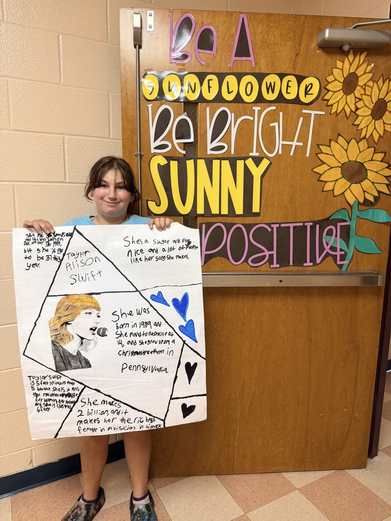 A student holds up a poster of an American who has made an impact 