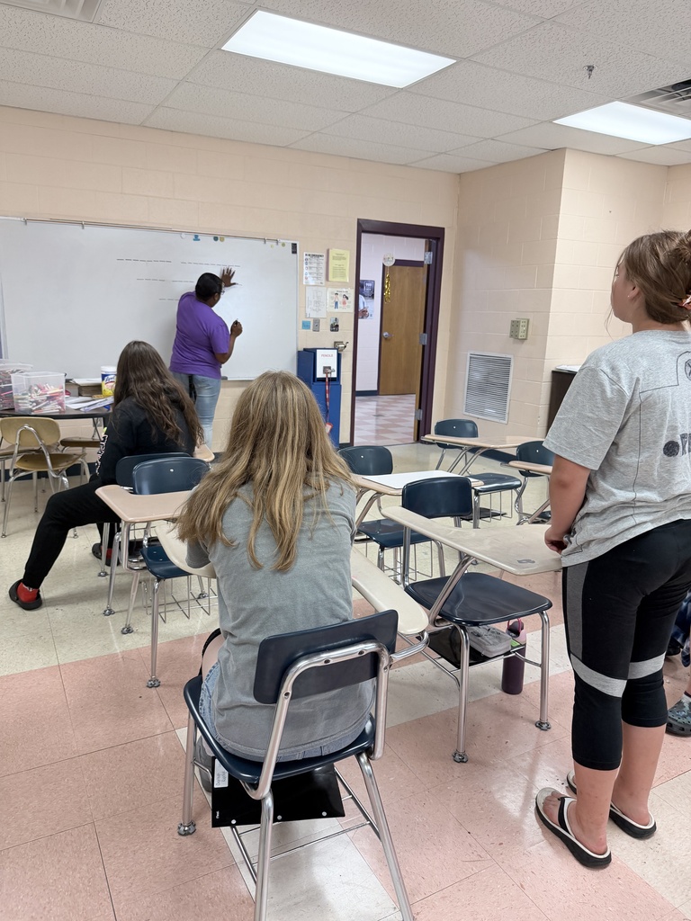 Students and their teacher are playing Wheel of Fortune on the white board. 