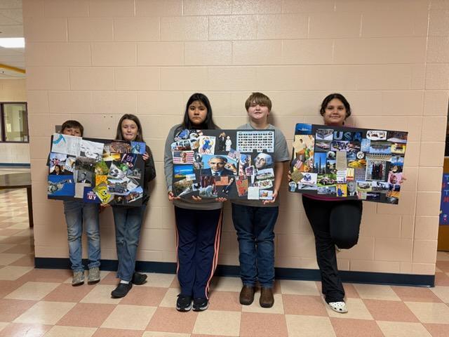 Five students are standing in the hallway holding up their American-themed collage poster. 