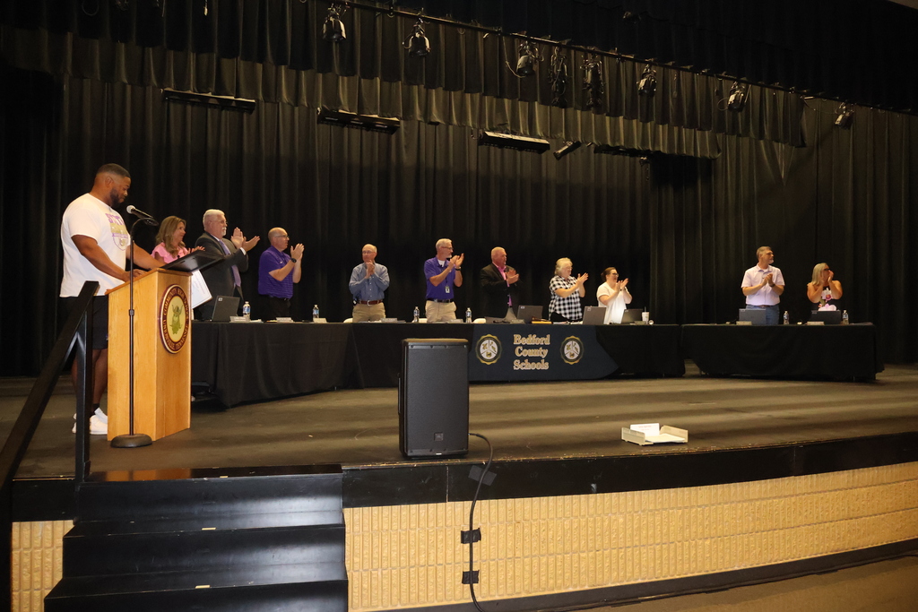 All of the school board members and superintendent are standing giving the players a round of applause. 