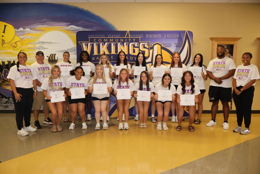 Community High School Viqueens Softball Team Players pose for a picture in the hallway while holding their certificates with their four coaches. 