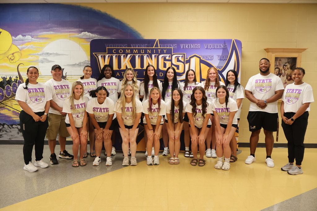 Community High School Viqueens Softball Team Players pose for a picture in the hallway with their four coaches. 