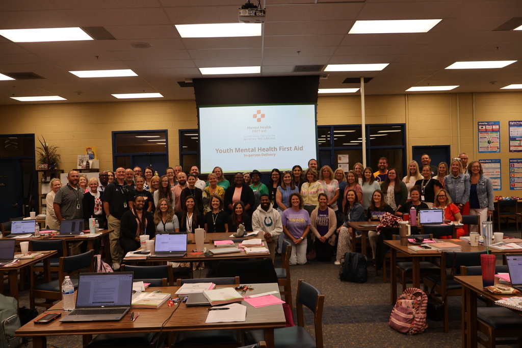 Principals, Assistant Principals and Supervisors are standing in the school's library posed for a group picture in front of a screen that says, "Youth Mental Health First Aid."