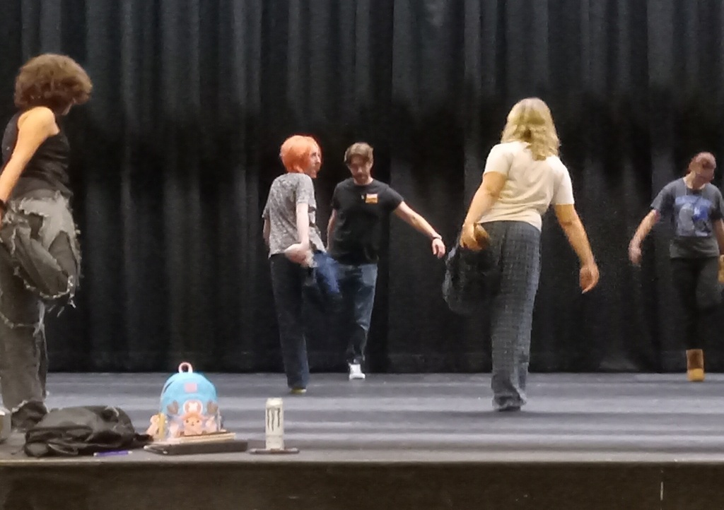 There are several students on the stage getting ready for rehearsals with exercises.