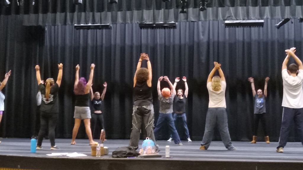 There are several students on the stage getting ready for rehearsals with exercises.