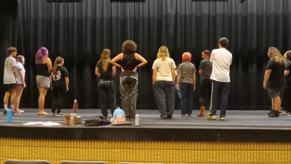 There are several students on the stage getting ready for rehearsals with exercises.