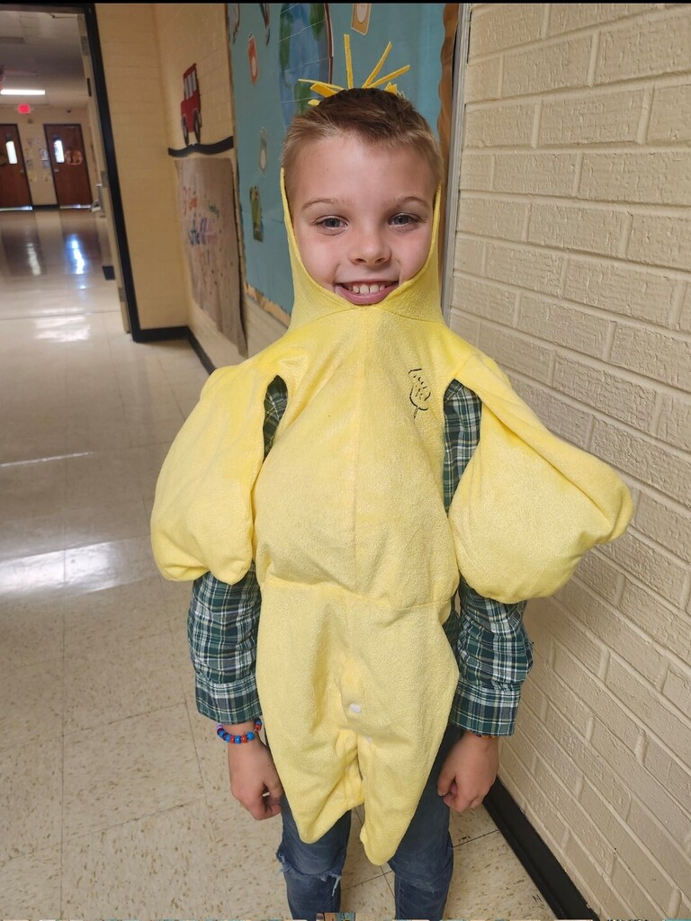 A student is dressed in a yellow costume standing in the hallway.