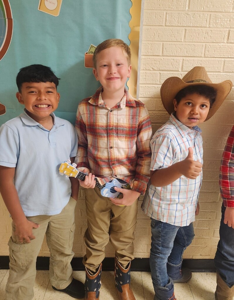Three students are standing in the hallway posed for a picture wearing their western wear.