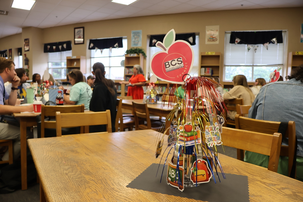 This is picture of a BCS Connect table decoration and you can see people behind it as they are listening to a speaker talk to them as they are seated at tables. 
