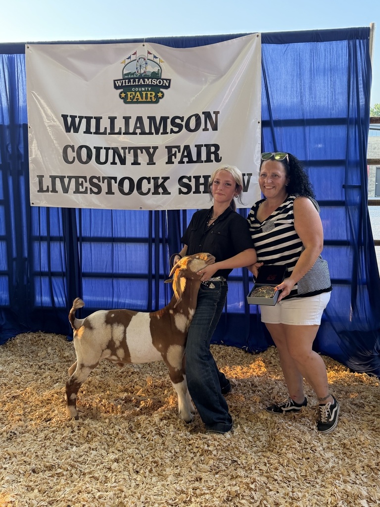 There are two people who are posed for a picture with one of them holding a goat that she had in the goat show.