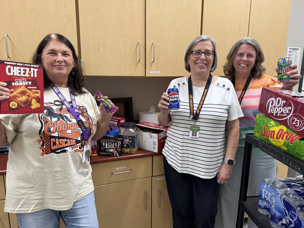 Four Cascade High School staff members displaying donated snacks and beverages including Cheez-Its, Pepsi, Dr Pepper, SunDrop, M&Ms and other treats.