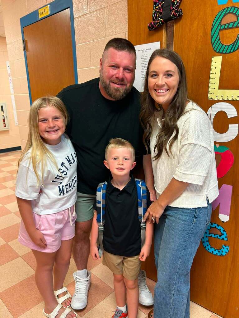 There are four people in this picture who are all posed for a group picture in the hallway of the school.