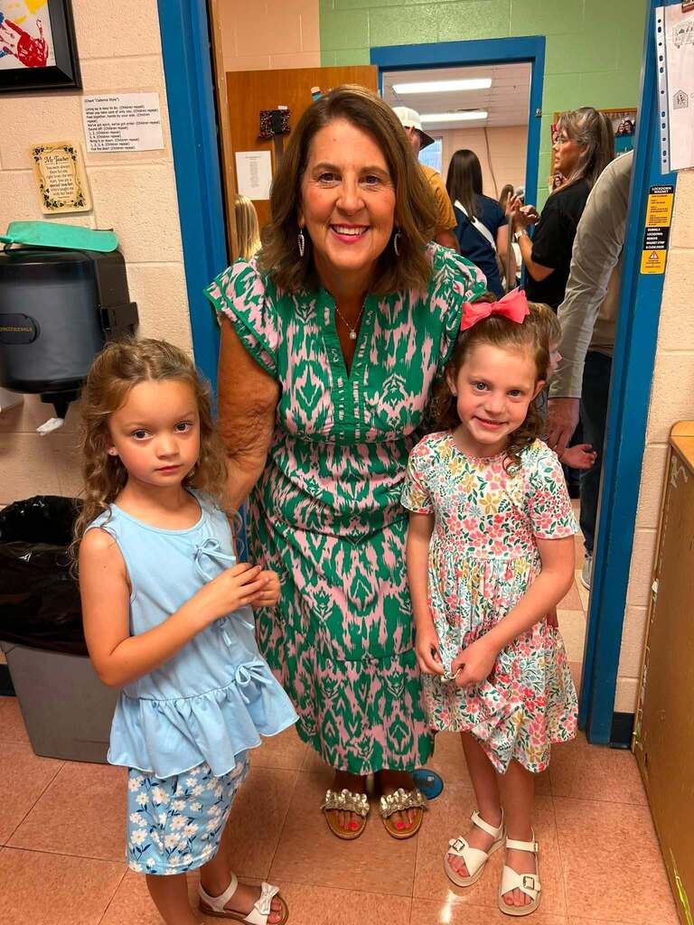 There are three people in this picture who are all posed for a group picture in the hallway of the school.