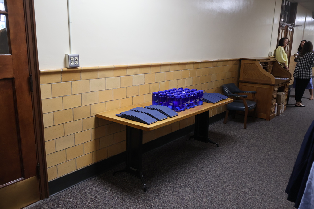 This is a table that has water bottles and books on it. 