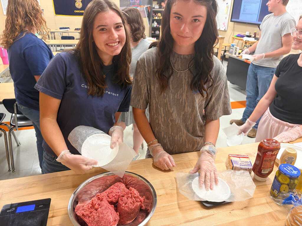 Two female students handling raw ground meat during veterinary science class hands-on activity at Cascade High School.
