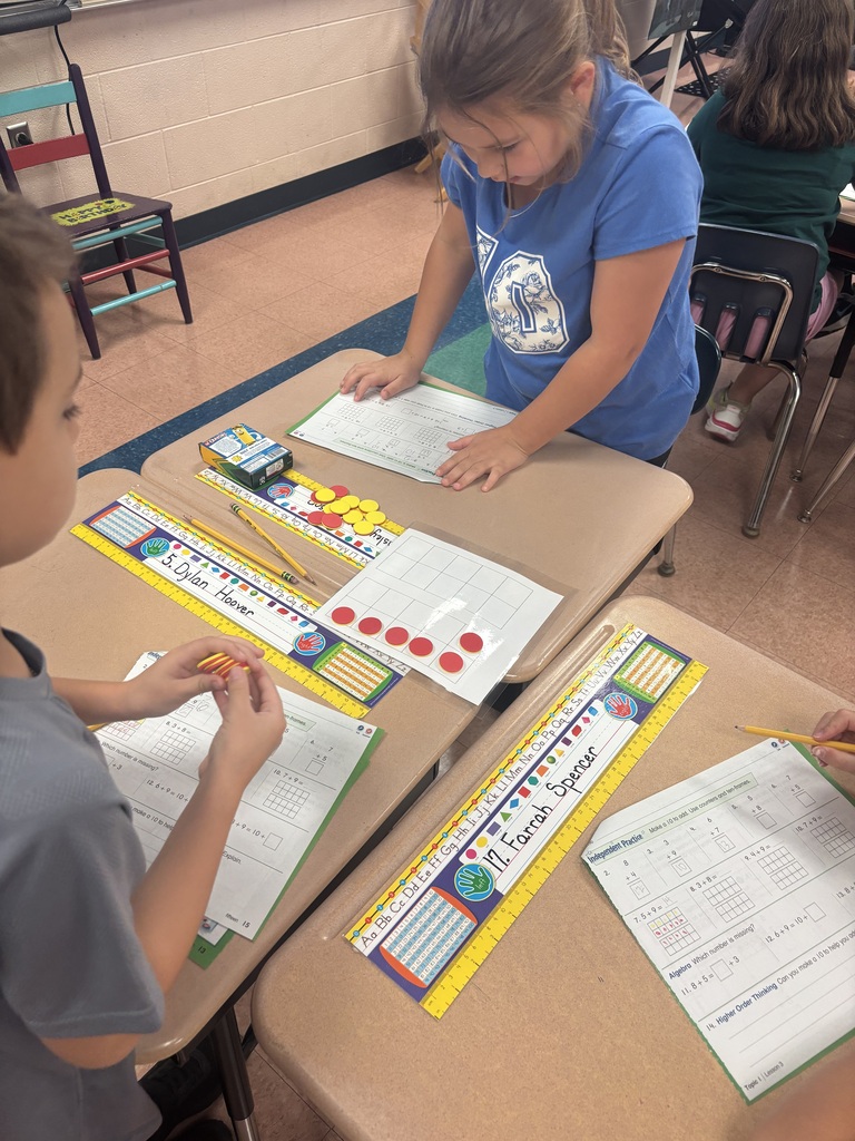 There are two students sitting at a desk while they are working on solving a math problem.