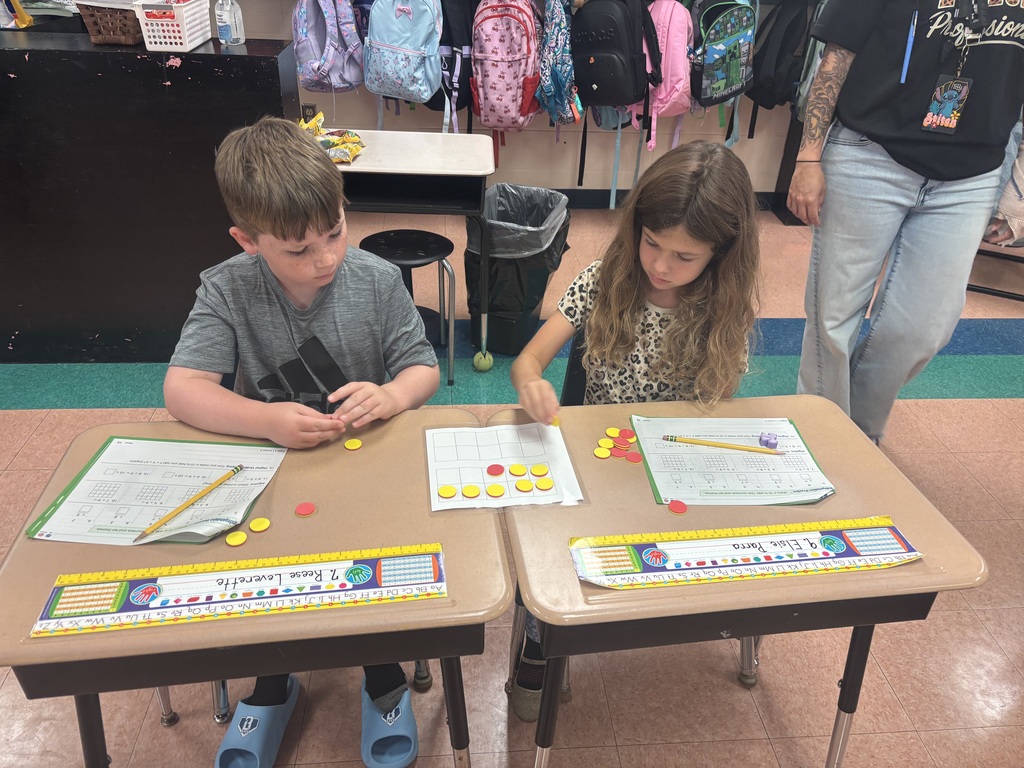 There are two students sitting at a desk while they are working on solving a math problem.