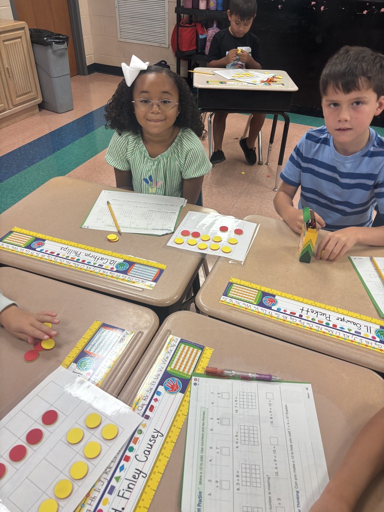 There are two students sitting at a desk while they are working on solving a math problem.