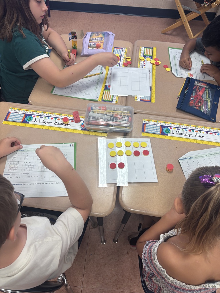There are four students sitting at a desk while they are working on solving a math problem.