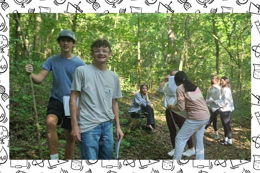 Students gathered on wooded trail during Physical Science outdoor scavenger hunt activity. 