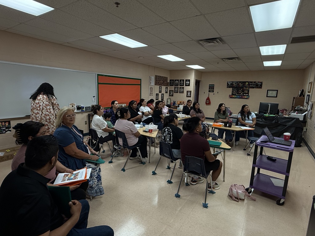 This is a picture of a classroom where several families are sitting at tables.