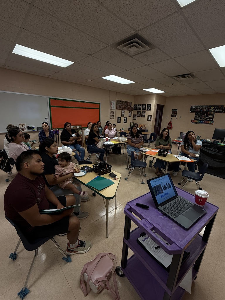 This is a picture of a classroom where several families are sitting at tables.