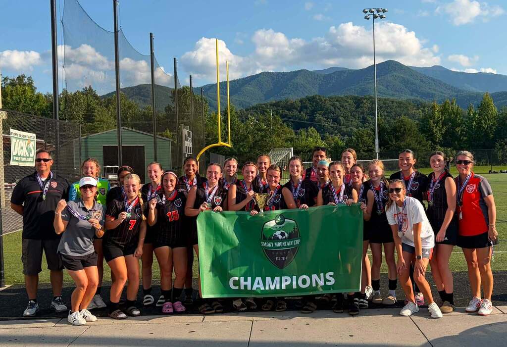  Cascade Lady Champions soccer team posing with "Champions" banner and medals after winning the Smoky Mountain Cup tournament in Gatlinburg with undefeated record.