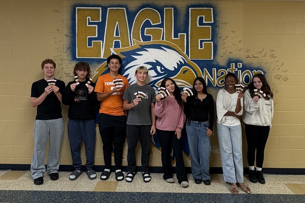 There are several students posed for a picture in the hallway and each are holding up a ticket to the Celebration. 