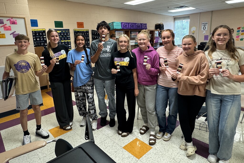 There are several students posed for a picture inside of a classroom and each are holding up a ticket to the Celebration. 