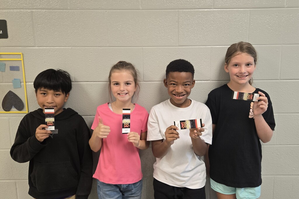 There are four students posed for a picture in the hallway and each are holding up a ticket to the Celebration. 