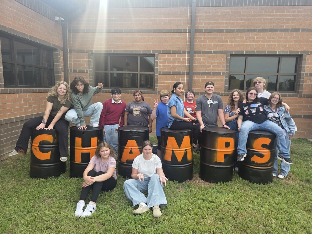 Group of students gathered around the Art Club's completed barrel project