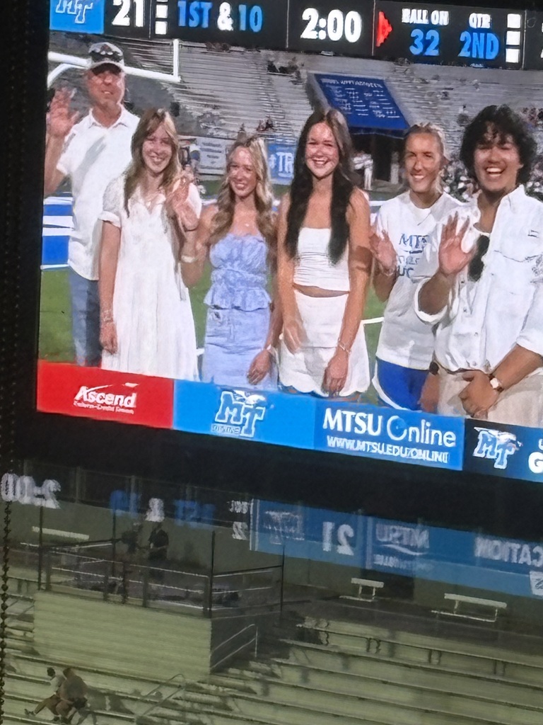 This is a group picture of six people, along with the Assistant Superintendent, on the football field at MTSU.