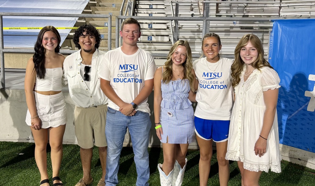 This is a group picture of six people on the football field at MTSU.