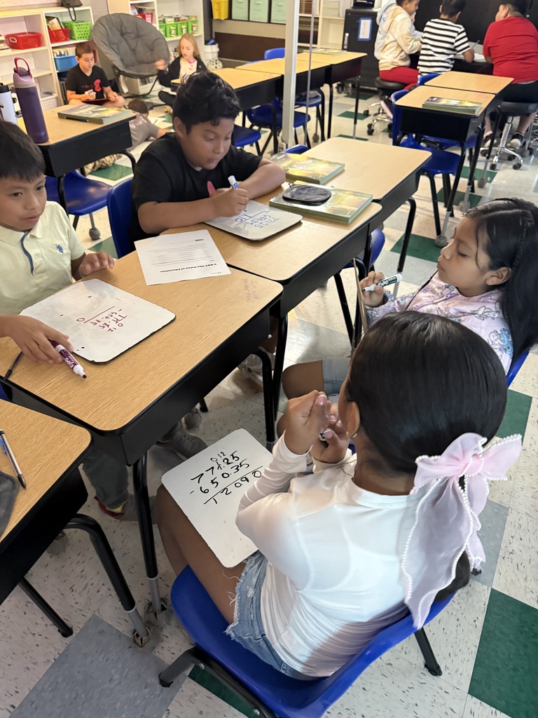 There are several students sitting at their desks all working on math problems in their classroom.