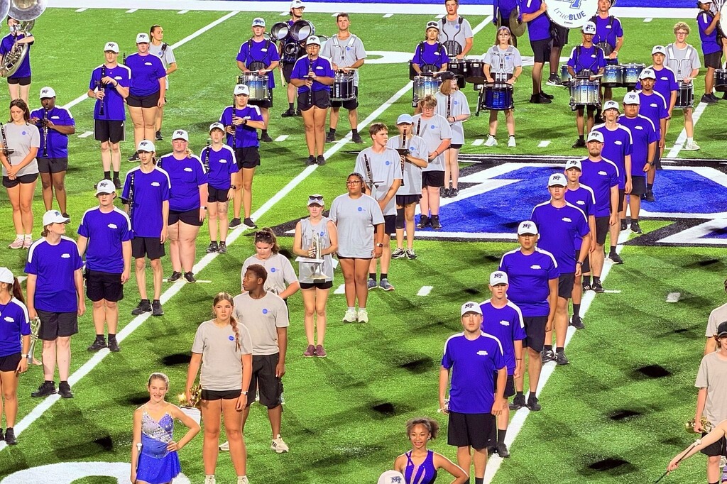 There are band members on the football field at MTSU all in a line.