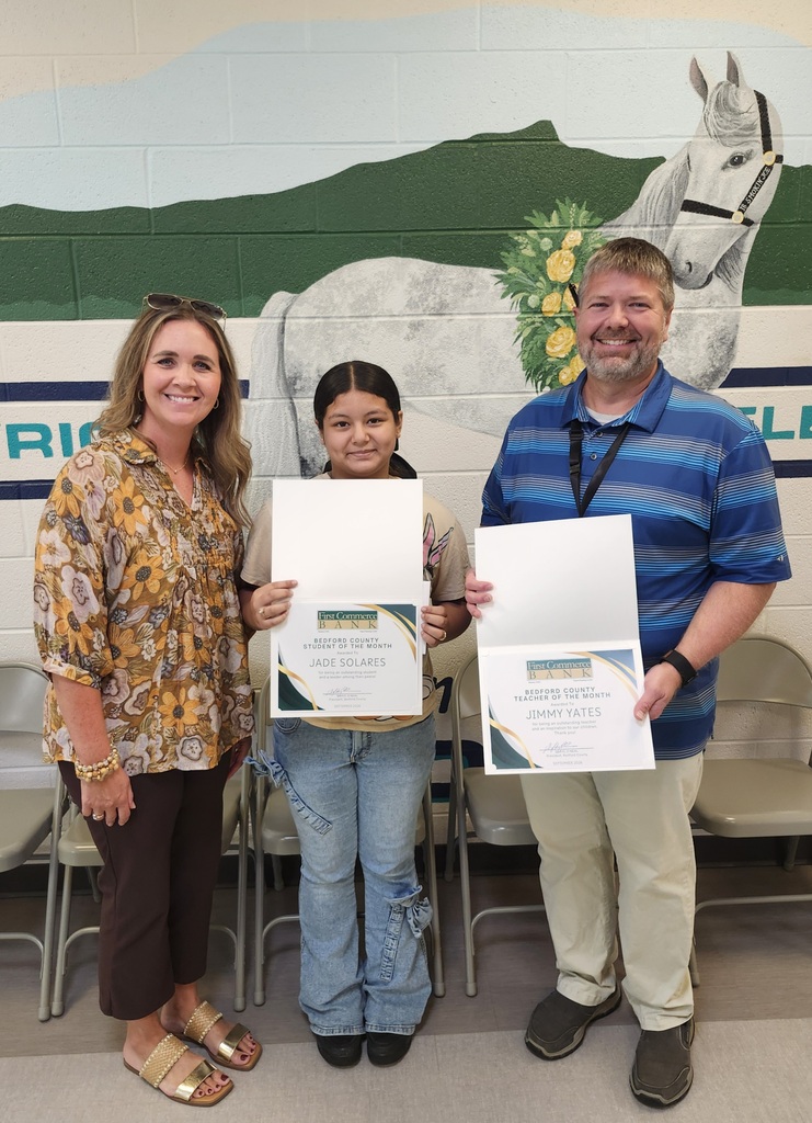 There are three people posed for a picture while two of them are holding up a certificate they were given.
