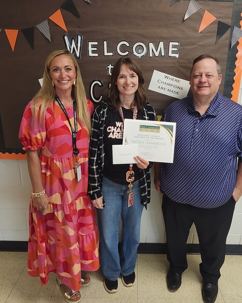 There are three people posed for a picture while one of them is holding up a certificate she was given.