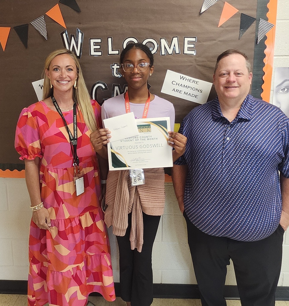 There are three people posed for a picture while one of them is holding up a certificate she was given.