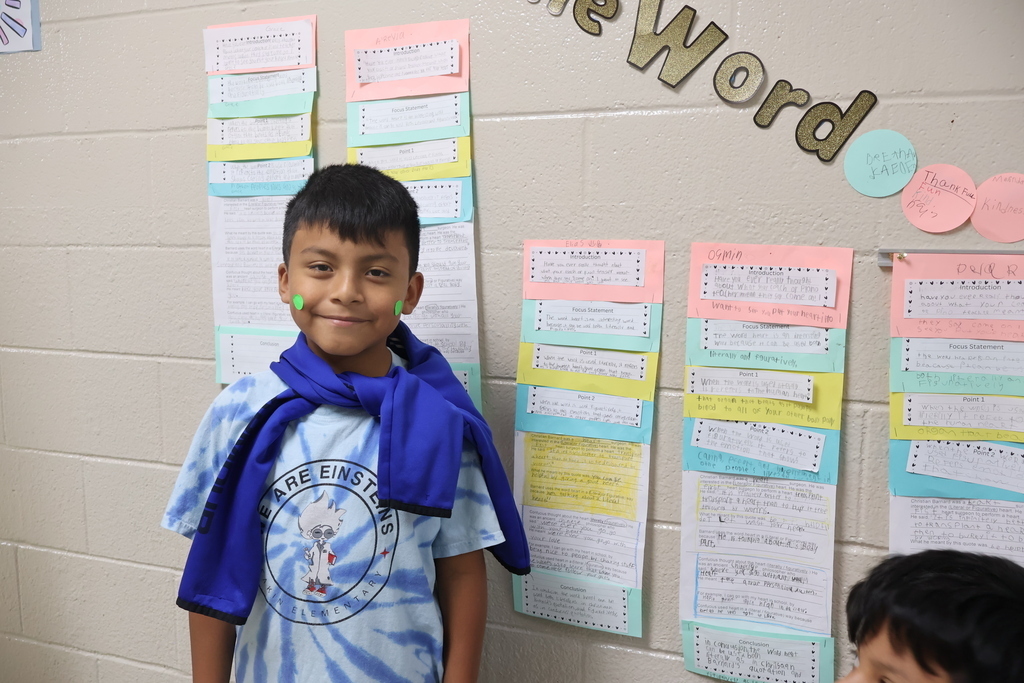 A student is posed for a picture beside the display of his essay.