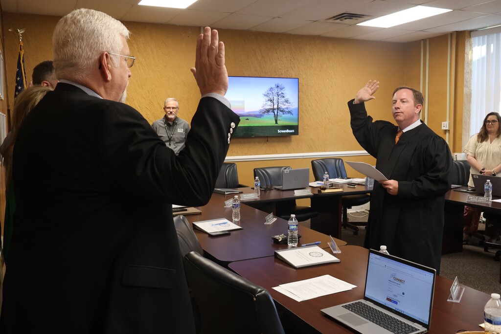 Four school board members are standing before a judge at the Central Office as they take their new Oath of Office for their new terms. The superintendent and another school board member are standing off to the side watching. 