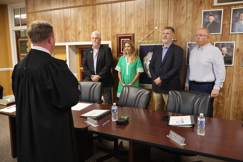 Four school board members are standing before a judge at the Central Office as they take their new Oath of Office for their new terms. 