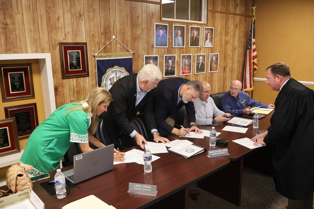 The four school board members are singing their Oaths of Office as the judge looks on. 
