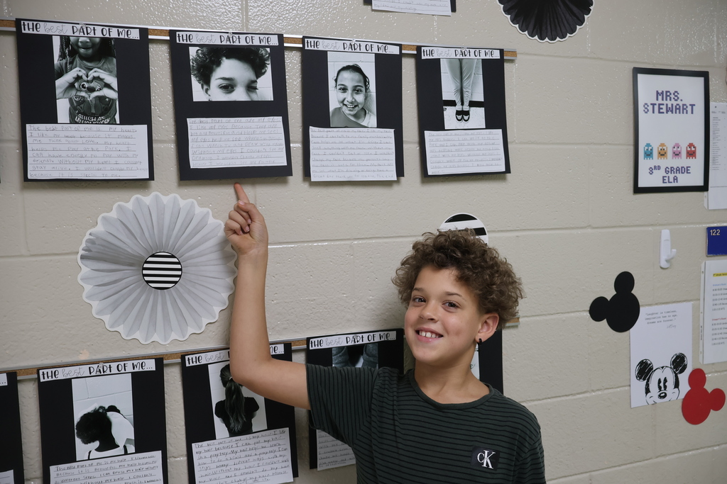 A boy points to the black and white picture she chose along with the writing she did underneath it. 
