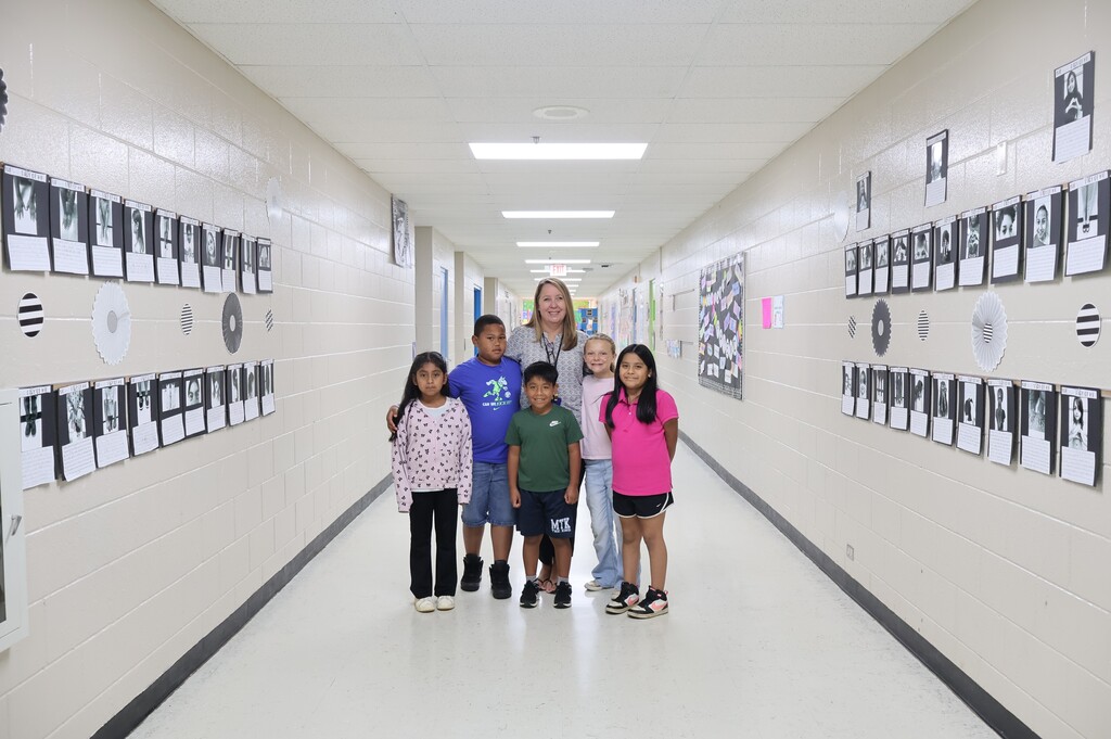 A teacher and five students are all posed in the hallway for a group picture. 
