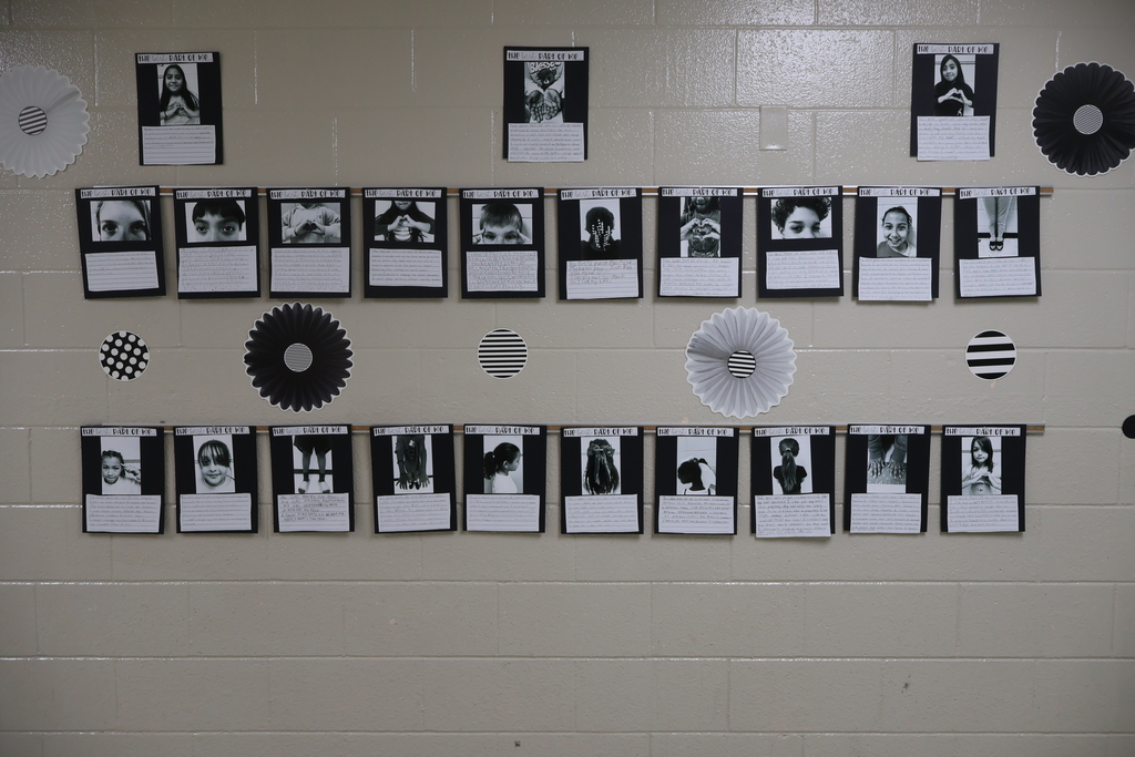 This is a picture of a wall with the black and white photos displayed on it. 
