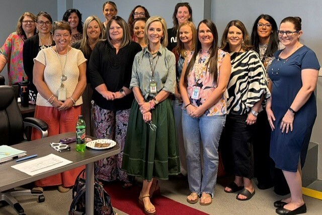 There are several people in this picture who are all posed for a group picture with Mrs. Susan Huff as this is her last meeting.